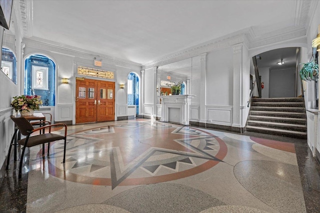 lobby with a decorative wall, crown molding, stairway, and wainscoting