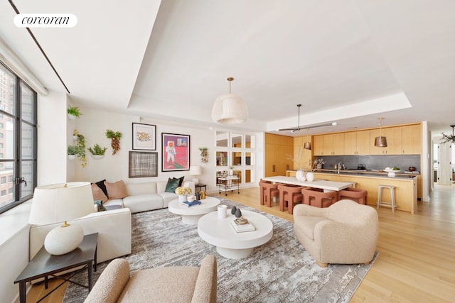 550 W 29th St Unit 9Afl, New York City, NY 10001 - living room featuring a tray ceiling, light wood-type flooring, and healthy amount of natural light
