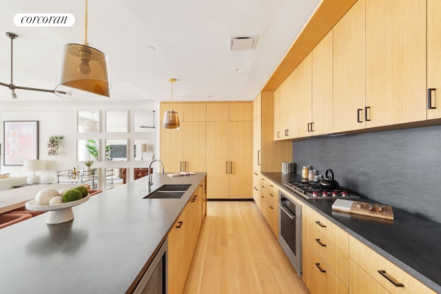 550 W 29th St Unit 9Afl, New York City, NY 10001 - kitchen with a sink, light brown cabinetry, stainless steel appliances, light wood-style flooring, and backsplash