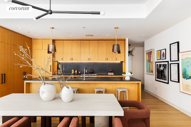 550 W 29th St Unit 9Afl, New York City, NY 10001 - kitchen featuring a sink, decorative backsplash, dark countertops, pendant lighting, and light wood-style floors