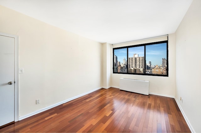 343 E 74th St Unit Ph2A, New York City, NY 10021 - spare room featuring radiator heating unit, hardwood / wood-style flooring, and a view of city