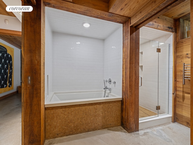 full bathroom featuring a stall shower, tiled bath, and concrete flooring