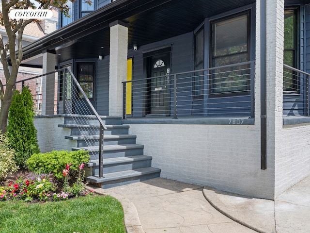 entrance to property featuring a porch and brick siding