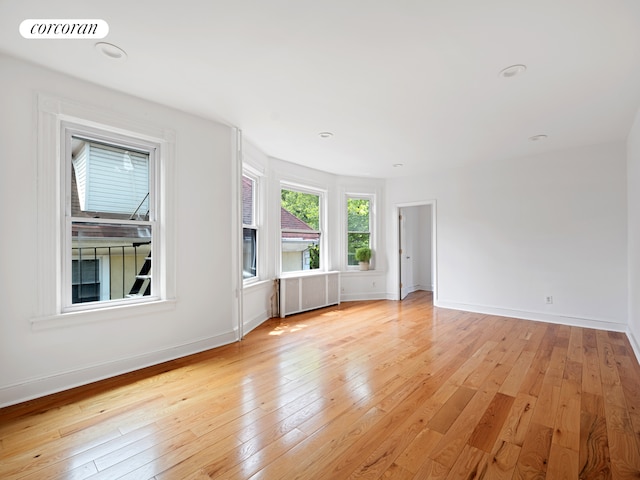unfurnished room with light wood-type flooring and baseboards