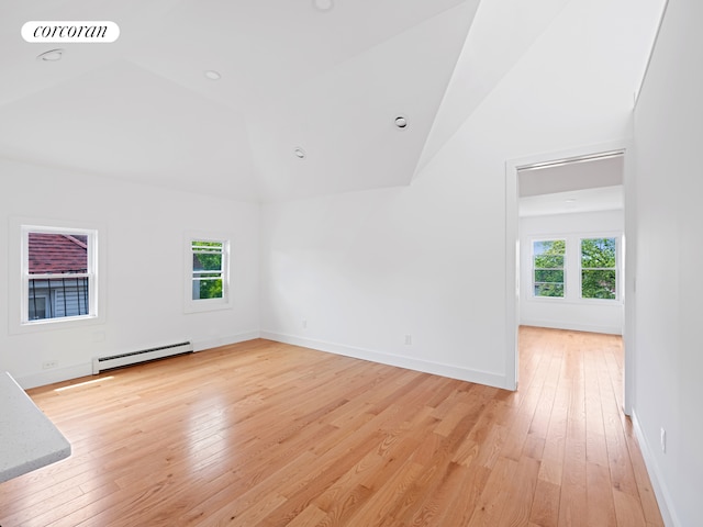 unfurnished room featuring a baseboard heating unit, lofted ceiling, light wood-style floors, and baseboards
