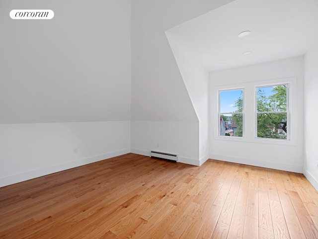 bonus room with a baseboard heating unit, light wood-style flooring, and baseboards