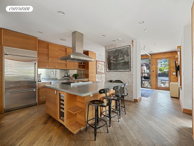 kitchen with stainless steel appliances, island range hood, a breakfast bar area, light wood-style floors, and recessed lighting
