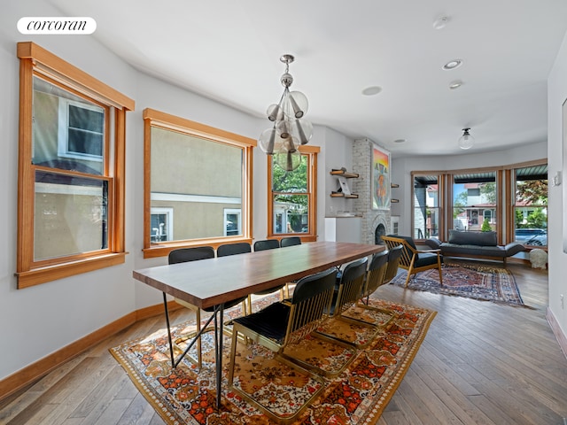 dining area featuring healthy amount of natural light, baseboards, light wood-type flooring, a fireplace, and recessed lighting