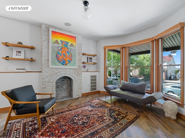 living area featuring wood-type flooring, a fireplace, and baseboards