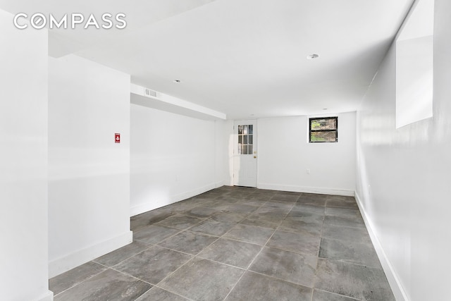 unfurnished room featuring baseboards and stone finish flooring