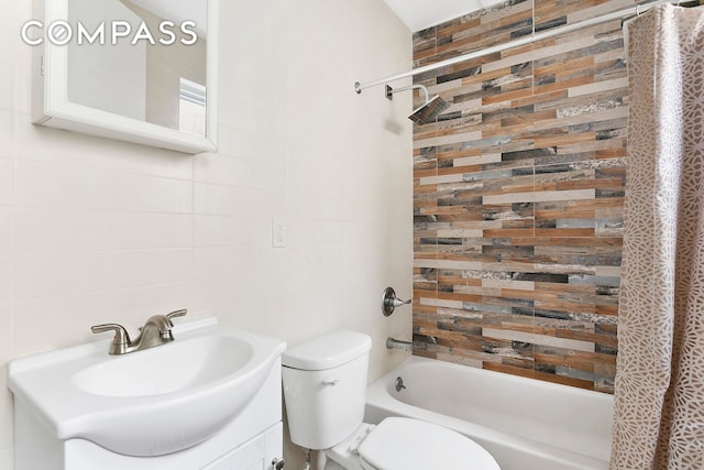 full bathroom featuring shower / bath combination with curtain, toilet, vanity, and tile walls