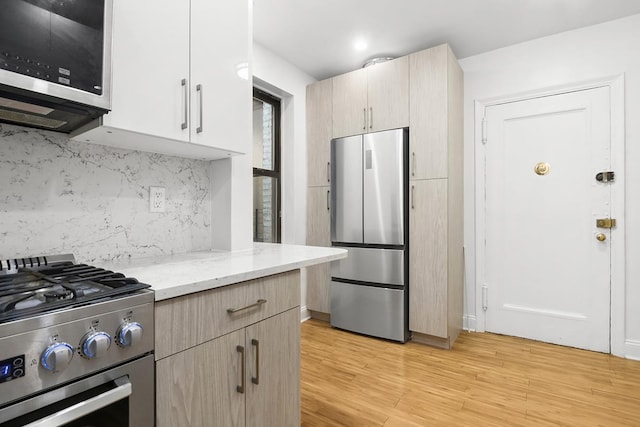 kitchen with stainless steel appliances, light wood finished floors, light stone counters, tasteful backsplash, and light brown cabinets