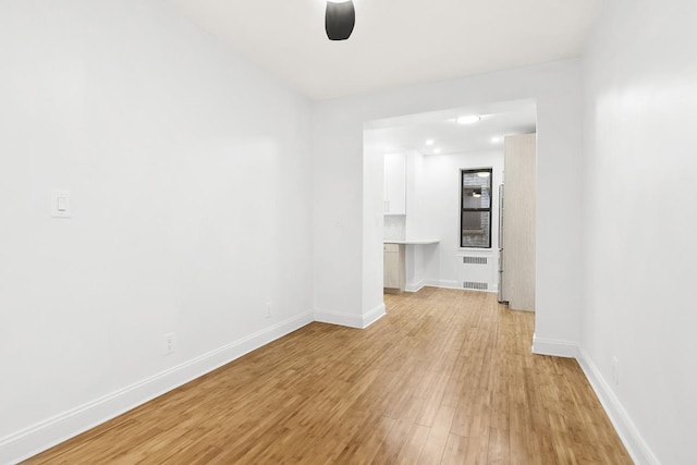unfurnished room featuring light wood finished floors, baseboards, and a ceiling fan