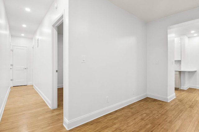 corridor featuring light wood-type flooring, baseboards, and recessed lighting