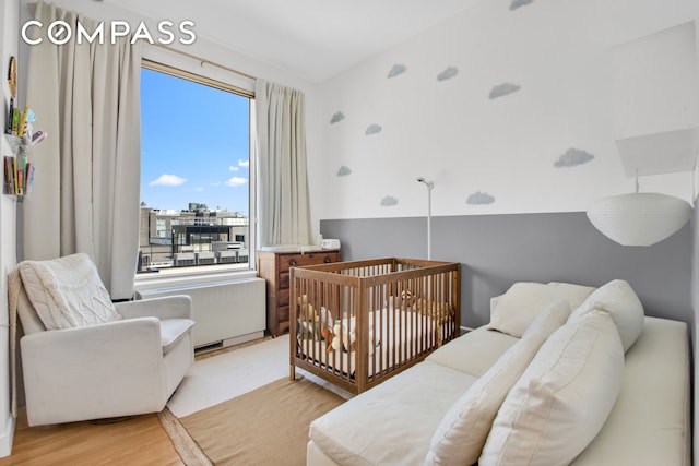 bedroom featuring light wood-style flooring and a crib