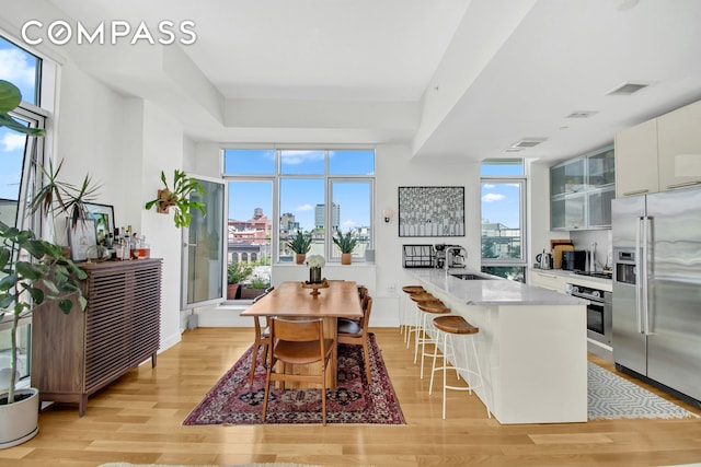 dining space featuring light wood-style flooring, a view of skyline, and baseboards