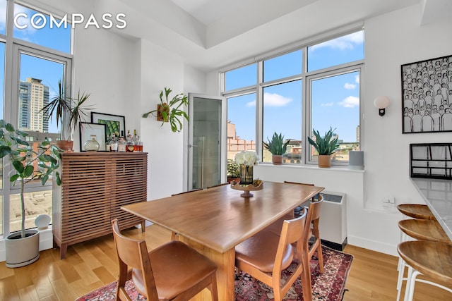 dining space with light wood-style flooring, baseboards, and a dry bar
