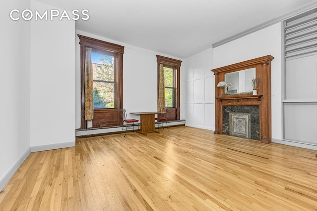 unfurnished living room with hardwood / wood-style floors, a high end fireplace, baseboards, crown molding, and a decorative wall