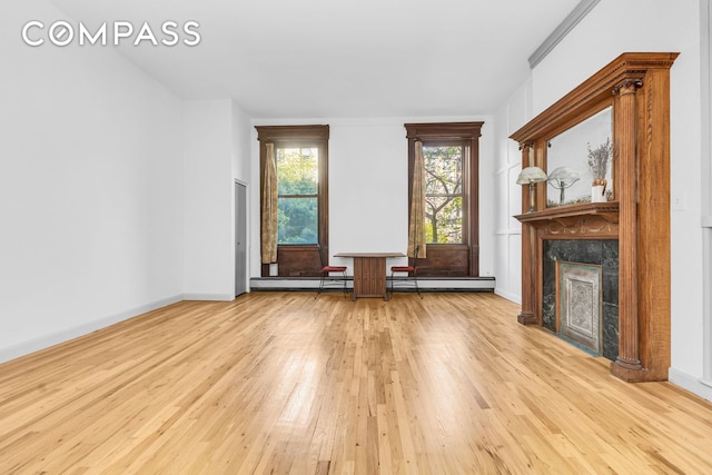 unfurnished living room featuring hardwood / wood-style floors, a premium fireplace, baseboards, and a baseboard radiator