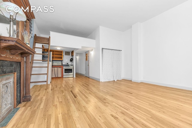 unfurnished living room with light wood-style flooring, a tile fireplace, and baseboards