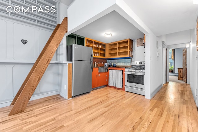 kitchen featuring appliances with stainless steel finishes, open shelves, light wood-type flooring, backsplash, and dark countertops