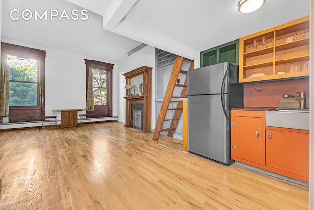 kitchen featuring freestanding refrigerator, a sink, light wood-style floors, and healthy amount of natural light