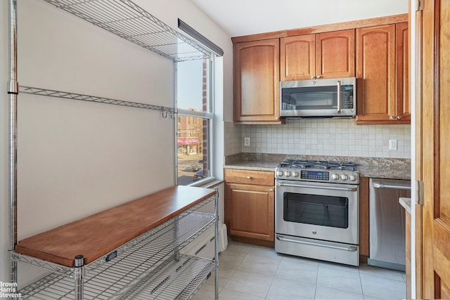 26-08 24th Ave, New York City, NY 11102 - kitchen featuring appliances with stainless steel finishes, tasteful backsplash, light tile patterned floors, and brown cabinets