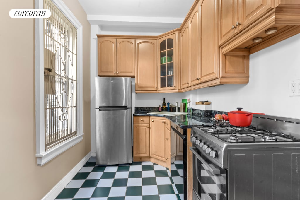 25 W 64th St Unit 2E, New York City, NY 10023 - kitchen with appliances with stainless steel finishes, tile patterned floors, glass insert cabinets, a sink, and baseboards