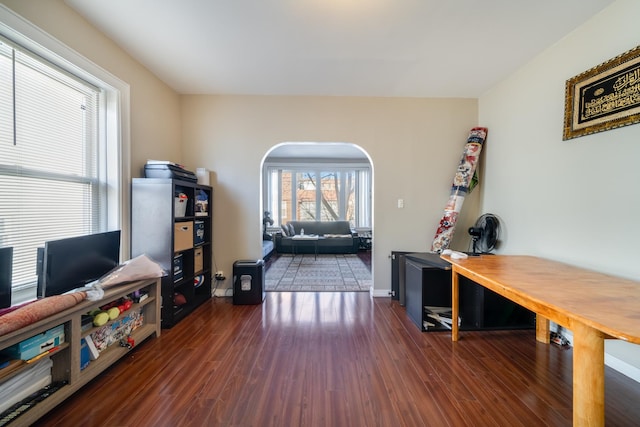 office area with wood finished floors and arched walkways