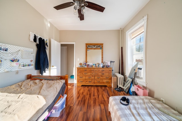 bedroom featuring wood finished floors, radiator heating unit, and ceiling fan