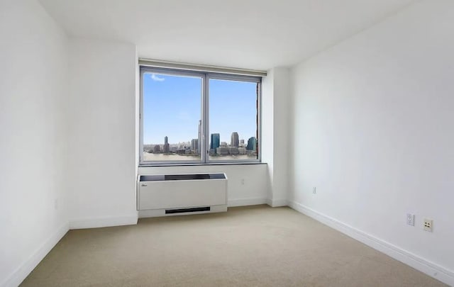 30 W St Unit 20F, New York City, NY 10004 - empty room featuring light colored carpet, baseboards, radiator heating unit, and a view of city