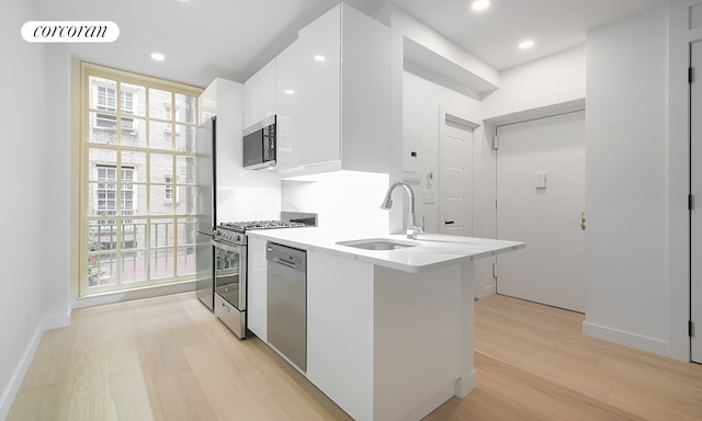 509 E 77th St Unit 1P, New York City, NY 10075 - kitchen featuring a sink, appliances with stainless steel finishes, white cabinetry, modern cabinets, and light wood finished floors