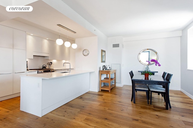 23 W 116th St Unit 11A, New York City, NY 10026 - kitchen with modern cabinets, a peninsula, white cabinetry, light wood-type flooring, and range