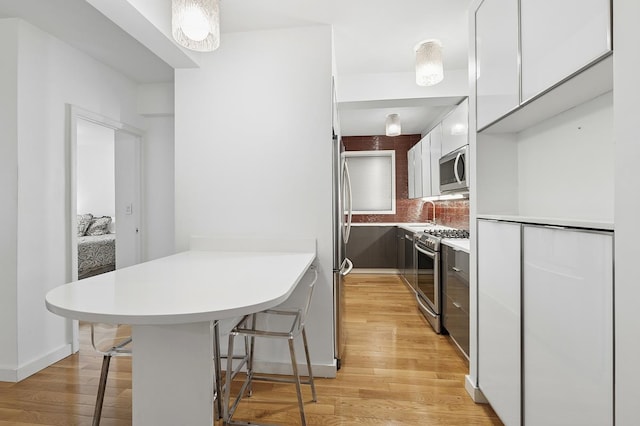 310 E 49th St Unit 4-D, New York City, NY 10017 - kitchen with modern cabinets, appliances with stainless steel finishes, a peninsula, white cabinetry, and a kitchen bar