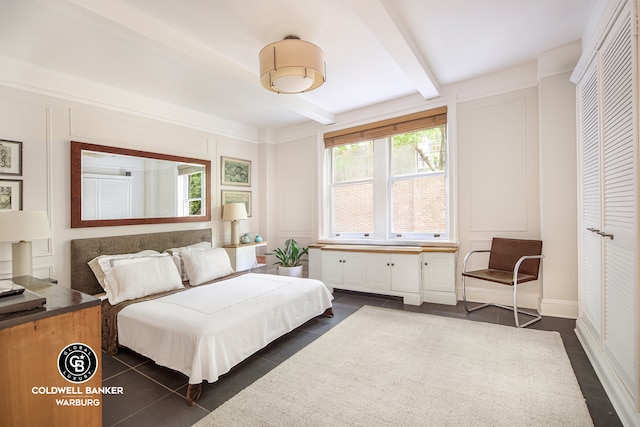 51 E 90th St Unit 1C, New York City, NY 10128 - bedroom with a decorative wall, beamed ceiling, and dark tile patterned floors