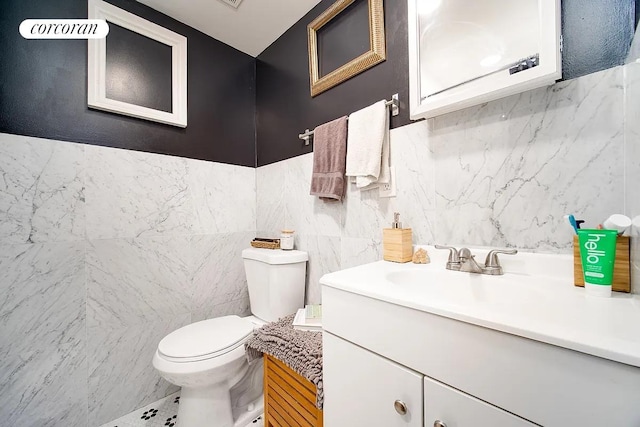 bathroom with vanity, toilet, and tile walls