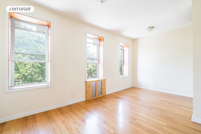 empty room with healthy amount of natural light, wood finished floors, and baseboards
