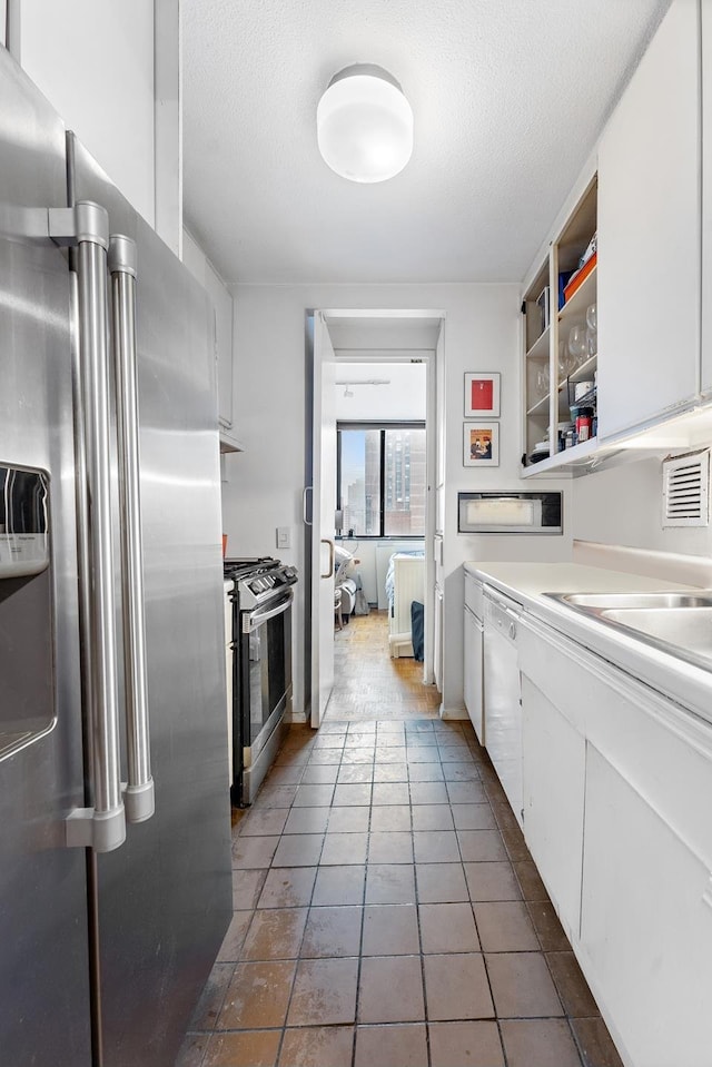 245 E 93rd St Unit 22C, New York City, NY 10128 - kitchen with appliances with stainless steel finishes, white cabinets, a textured ceiling, light countertops, and tile patterned floors