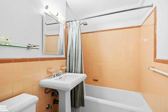 123 E 37th St Unit 6B, New York City, NY 10016 - full bath featuring toilet, shower / tub combo with curtain, tile walls, and a wainscoted wall
