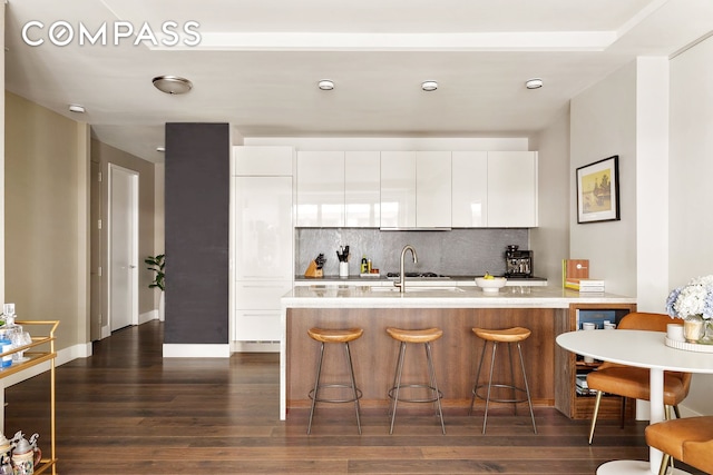 4 W 21st St Unit 2D, New York City, NY 10010 - kitchen with modern cabinets, decorative backsplash, a breakfast bar, and dark wood finished floors