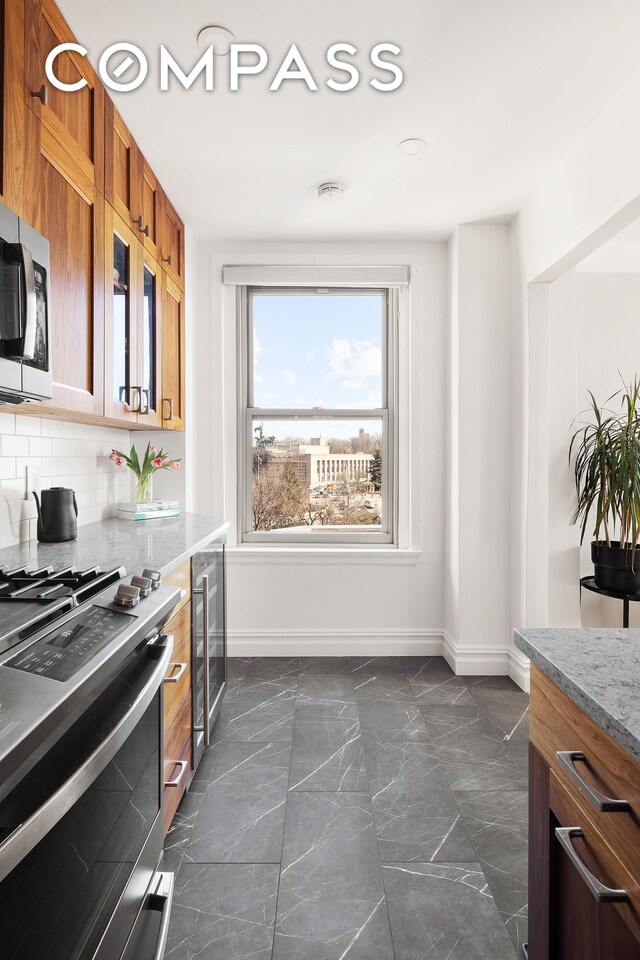 39 Plaza St W Unit 7C, New York City, NY 11217 - kitchen with appliances with stainless steel finishes, baseboards, wine cooler, dark marble finish floors, and brown cabinetry