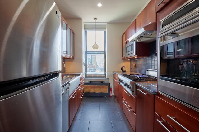 75 Livingston St Unit 28-A, New York City, NY 11201 - kitchen with stainless steel appliances, under cabinet range hood, decorative backsplash, dark tile patterned flooring, and decorative light fixtures