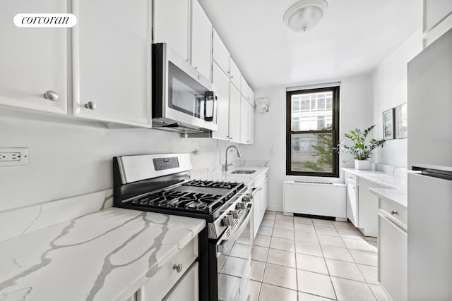 500 E 83rd St Unit 3D, New York City, NY 10028 - kitchen featuring stainless steel appliances, a sink, white cabinets, light tile patterned flooring, and light stone countertops