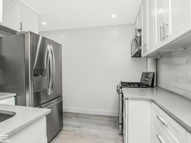 5639 Netherland Ave Unit 5C, New York City, NY 10471 - kitchen with appliances with stainless steel finishes, white cabinets, decorative backsplash, recessed lighting, and light stone counters