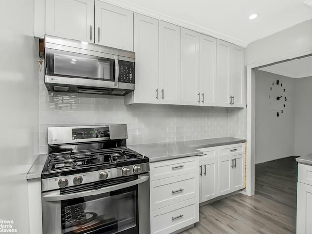5639 Netherland Ave Unit 5C, New York City, NY 10471 - kitchen with appliances with stainless steel finishes, backsplash, light wood-style floors, white cabinetry, and light countertops