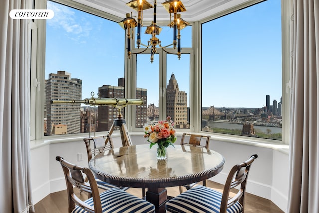 dining space with a skyline view, baseboards, wood finished floors, and a chandelier