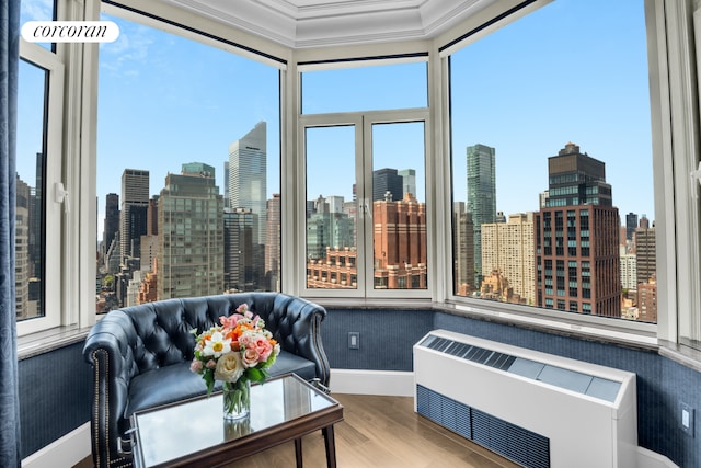 sunroom featuring baseboards, wood finished floors, a view of skyline, and ornamental molding