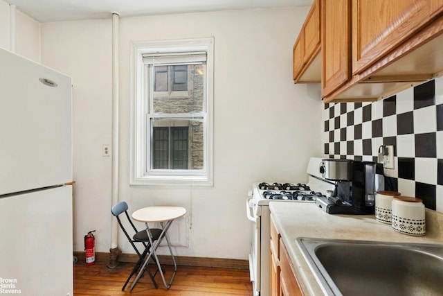 128 W 138th St Unit 3H, New York City, NY 10030 - kitchen with white appliances, light wood-style flooring, light countertops, and brown cabinets