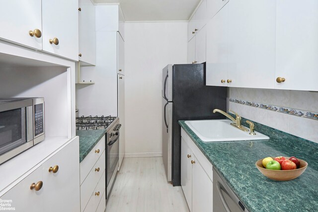 225 E 76th St Unit 4A, New York City, NY 10021 - kitchen featuring a sink, stainless steel appliances, dark countertops, and white cabinets