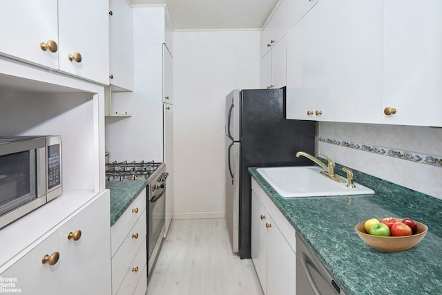 225 E 76th St Unit 4A, New York City, NY 10021 - kitchen featuring a sink, appliances with stainless steel finishes, dark countertops, and white cabinetry